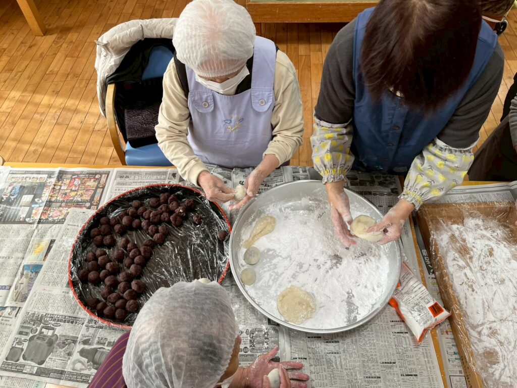 昔取った杵柄で見事な手つき。蒸し上がったお餅を笑顔で手早く丸める女性利用者様たち。指先の生活リハビリテーション