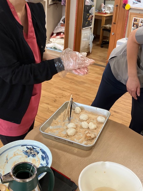 ご利用者様がビニール手袋をして、手作りおはぎを握っている様子。